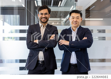 Two professional businessmen standing with arms crossed in modern office setting. They exude confidence and professionalism, symbolizing teamwork and leadership in business environment. Two professional businessmen standing with arms crossed in modern office setting. They exude confidence and professionalism, symbolizing teamwork and leadership in business environment. 122644081