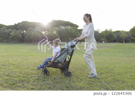 Happy family walking in park with baby stroller at sunset 122645300