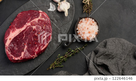 Raw beef steak chuck eye roll on a blck board. Spices for cooking Himalayan salt, peppercorns and thyme sprigs Raw beef steak chuck eye roll on a blck board. Spices for cooking Himalayan salt, peppercorns and thyme sprigs 122646146
