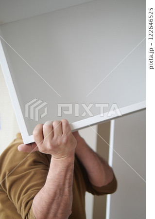 Person lifting a large white board while working on home organization 122646525