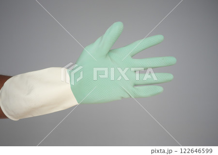 Green rubber glove on a hand for various tasks 122646599