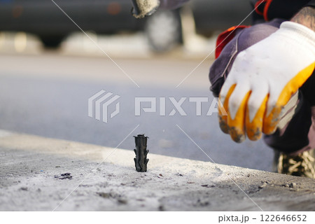 Close-Up of Construction Worker Installing Anchor Bolts in Concrete Surface Close-Up of Construction Worker Installing Anchor Bolts in Concrete Surface 122646652