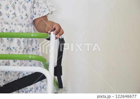 A Child Utilizing a Green Walker Designed for Support and Improved Mobility Skills A Child Utilizing a Green Walker Designed for Support and Improved Mobility Skills 122646677