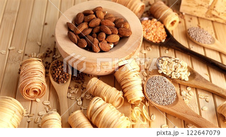 Wooden spoons and bowl holding organic ingredients like almonds, oats, chia seeds, buckwheat in natural setting. Minimalist design focusing on sustainability food choices Organic wood 122647079