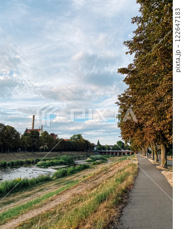 Path runs along a river bank with trees on either side 122647183