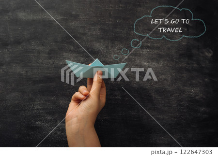 A hand holding a paper boat with the words Let's go to travel 122647303
