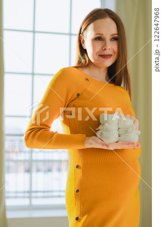 Pregnancy motherhood people expectation future. Pregnant woman with big belly holding newborn baby booties smiling at home. Young mom enjoying pregnancy. Maternity tenderness parenthood new life Pregnancy motherhood people expectation future. Pregnant woman with big belly holding newborn baby booties smiling at home. Young mom enjoying pregnancy. Maternity tenderness parenthood new life 122647968