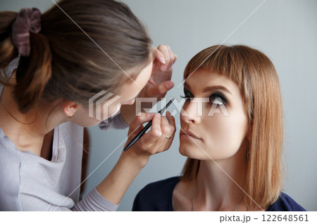 makeup artist glues false eyelashes 122648561