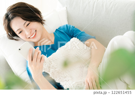 寝転んでスマホを見る若い女性 122651455