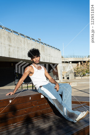 Young Latino man sitting on a wooden platform in a square 122651834