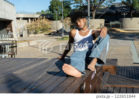 Young Latino man sitting on a wooden platform in a square 122651844