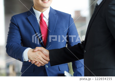 Asian businesspeople having a discussion together while walking inside the office building. Manager is talking with senior manager or chief of management. Businessmen in action portrait. 122654155