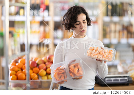 Adult woman chooses prawns in grocery store 122654508