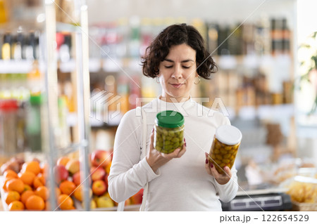 In store, woman near counter are looking at pickled green olives jar 122654529