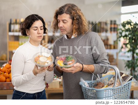 Couple man and woman choosing poke in grocery store Couple man and woman choosing poke in grocery store 122654780