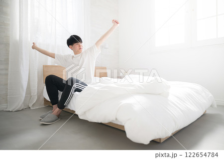 朝日を浴びるベッドで寝起きの若い男性の広角　よく寝た～ 122654784