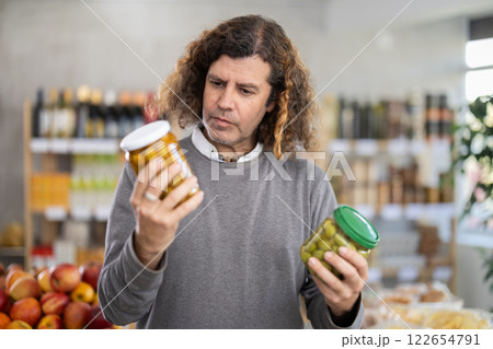 Adult man choosing olives in grocery store Adult man choosing olives in grocery store 122654791