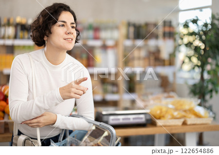 In store, woman looking for something on shelf of showcase In store, woman looking for something on shelf of showcase 122654886