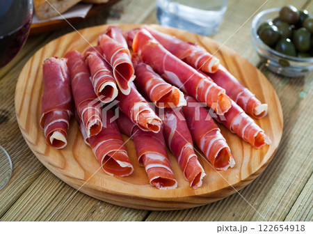 Spanish tapas - rolls of jamon serrano served on wooden board Spanish tapas - rolls of jamon serrano served on wooden board 122654918