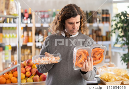 Adult man chooses prawns in grocery store 122654966