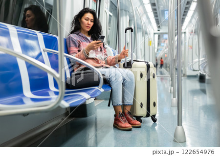 Woman passenger using phone in subway car Woman passenger using phone in subway car 122654976