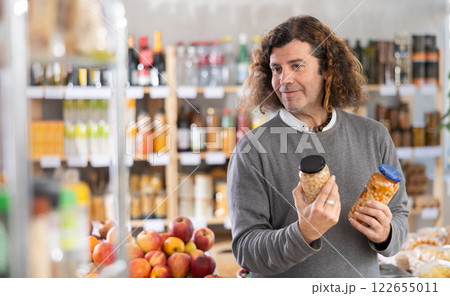 Man choosing cans of beans Man choosing cans of beans 122655011