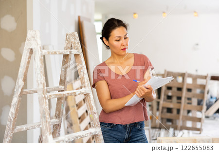 Woman designer checking documents during repair works Woman designer checking documents during repair works 122655083