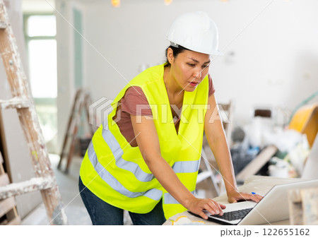 Woman builder using laptop in construction site Woman builder using laptop in construction site 122655162