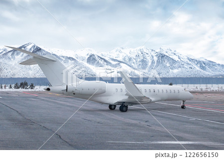 White luxury executive aircraft on airport in winter on the background of high picturesque snow capped mountains White luxury executive aircraft on airport in winter on the background of high picturesque snow capped mountains 122656150