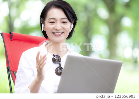 ワーケーション　公園からオンラインミーティングに参加するミドル女性 122656903