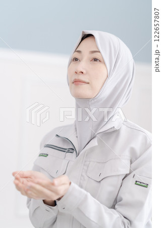 会社の礼拝室でお祈りをする作業着のミドルの女性 122657807