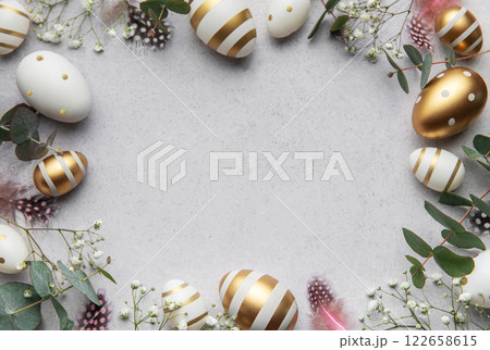 Easter eggs frame decorating a gray surface with eucalyptus leaves and feathers Easter eggs frame decorating a gray surface with eucalyptus leaves and feathers 122658615