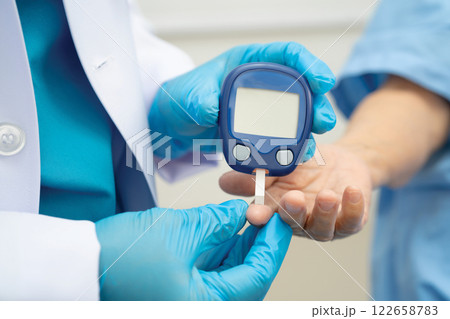 Asian doctor using digital glucose meter for check sample blood sugar level to treatment diabetes. Asian doctor using digital glucose meter for check sample blood sugar level to treatment diabetes. 122658783