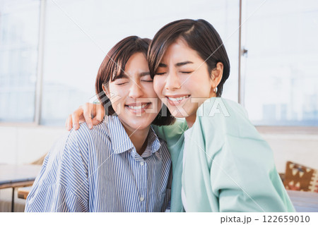 笑顔で目をつぶり顔を寄せ合う30代の2人の友達の女性 122659010