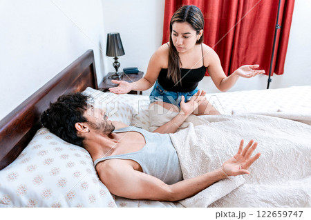 Young couple arguing in bed room. Husband fighting with his wife in bed. Concept of couple problems in bed. Upset woman with husband in bedroom bed Young couple arguing in bed room. Husband fighting with his wife in bed. Concept of couple problems in bed. Upset woman with husband in bedroom bed 122659747