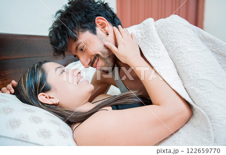 Couple waking up with a kiss in the morning, Man waking up woman with a kiss in bed. Couple in love in bed looking at each other with love Couple waking up with a kiss in the morning, Man waking up woman with a kiss in bed. Couple in love in bed looking at each other with love 122659770