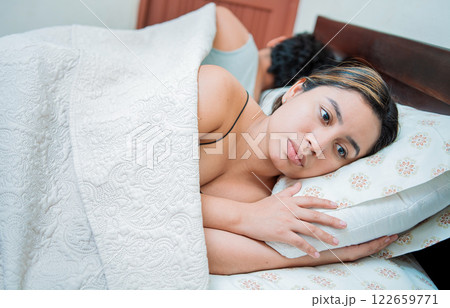 Upset couple sleeping on their backs. Young couple arguing and sleeping apart. Concept of couple problems in bed. Unhappy couple in bed sleeping apart Upset couple sleeping on their backs. Young couple arguing and sleeping apart. Concept of couple problems in bed. Unhappy couple in bed sleeping apart 122659771