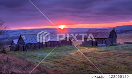 Old rustic barns cluster in the rolling countryside, bathed in the hues of a violet sunset. Serenity abounds. 122660189