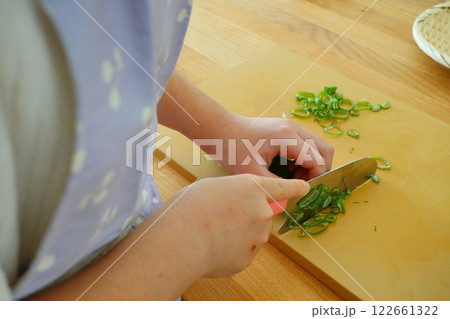 小学生の子供が包丁でネギを切っている手元 122661322