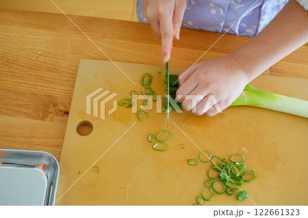 小学生の子供が包丁でネギを切っている手元 122661323