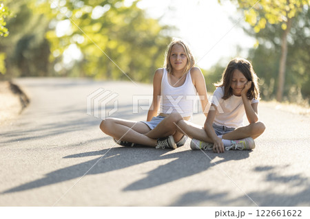 Two children relaxing on a sunlit pathway Two children relaxing on a sunlit pathway 122661622