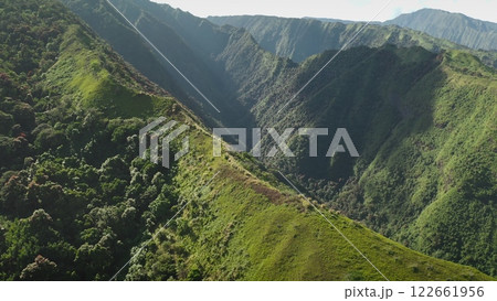 Aerial drone footage captures the breathtaking beauty of a lush green valley nestled between steep, vibrant mountains in kauai, hawaii, showcasing the untouched wilderness of the tropics 122661956
