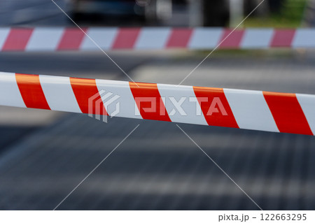 A striking warning barrier stretches across a city street, signaling danger and preventing unauthorized entry during daylight hours A striking warning barrier stretches across a city street, signaling danger and preventing unauthorized entry during daylight hours 122663295