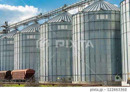 Grain storage. Silos on agro-processing and manufacturing plant for processing drying cleaning and storage of agricultural products. Modern steel agricultural grain granary silos. Agribusiness Grain storage. Silos on agro-processing and manufacturing plant for processing drying cleaning and storage of agricultural products. Modern steel agricultural grain granary silos. Agribusiness 122663368