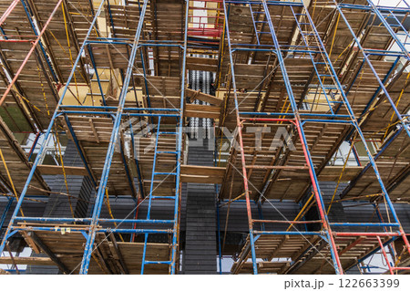 Scaffolding structures surround the building site as workers focus on construction activities, facilitating the development of infrastructure Scaffolding structures surround the building site as workers focus on construction activities, facilitating the development of infrastructure 122663399