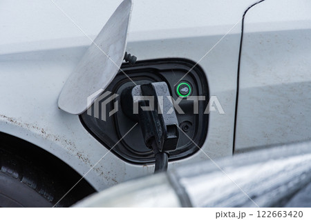 An electric vehicle is connected to a charging station, highlighting advancements in renewable energy and efficient transportation solutions 122663420