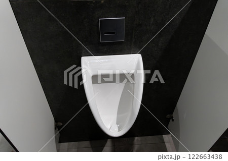 Minimalist urinal situated in a clean, modern restroom, highlighting hygiene and comfort in a public setting for male users 122663438
