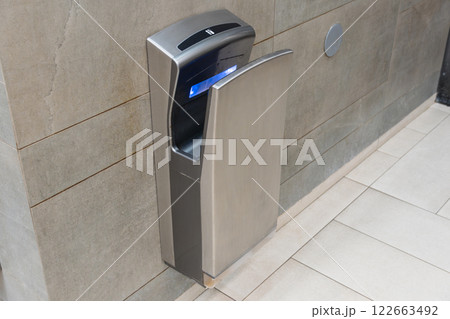 Cutting-edge hand drying equipment is installed in a stylish bathroom, promoting sanitation and modern convenience for users 122663492