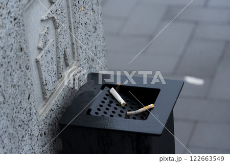 Cigarette butts are discarded in a waste container, emphasizing the ongoing need for better waste management practices in urban areas Cigarette butts are discarded in a waste container, emphasizing the ongoing need for better waste management practices in urban areas 122663549