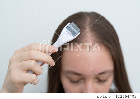 Close up view, young woman using microneedling derma roller on head for stimulating new hair growth with copy space. Alopecia treatment, scalp stimulation, hair loss and baldness targeted therapy. Close up view, young woman using microneedling derma roller on head for stimulating new hair growth with copy space. Alopecia treatment, scalp stimulation, hair loss and baldness targeted therapy. 122664483